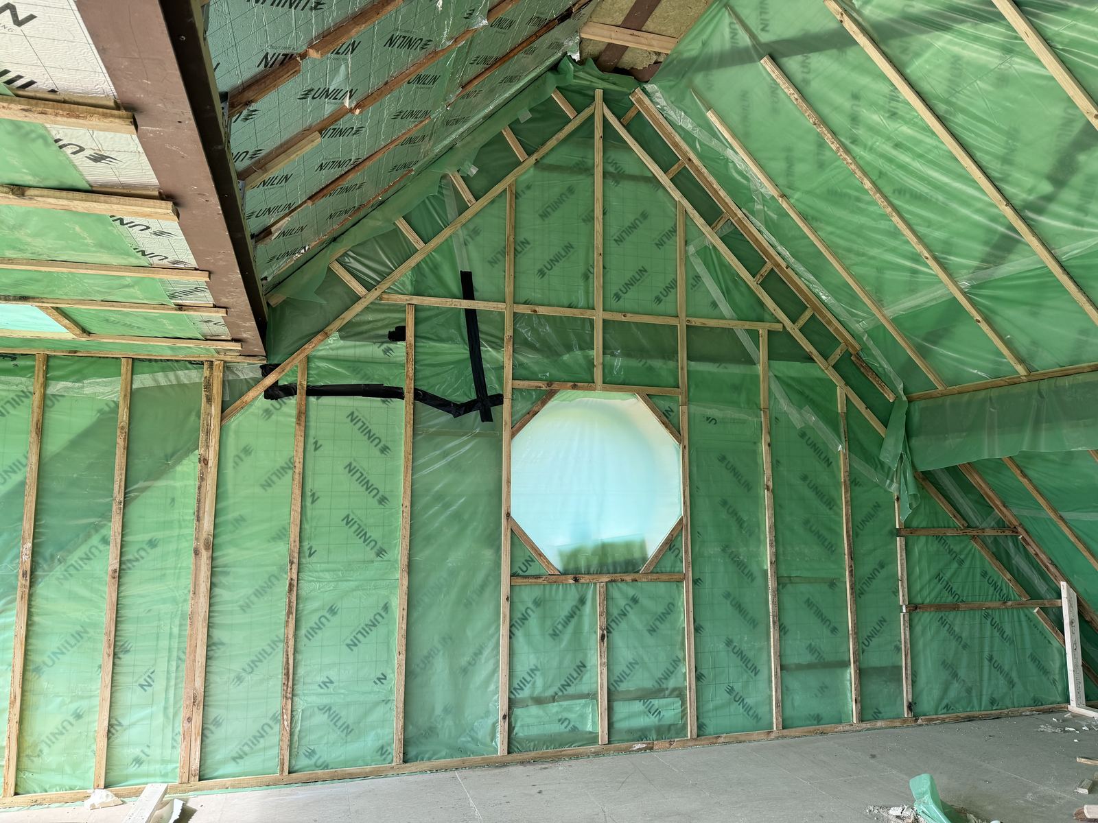 Airtightness membrane taped across a new roof structure with a round window